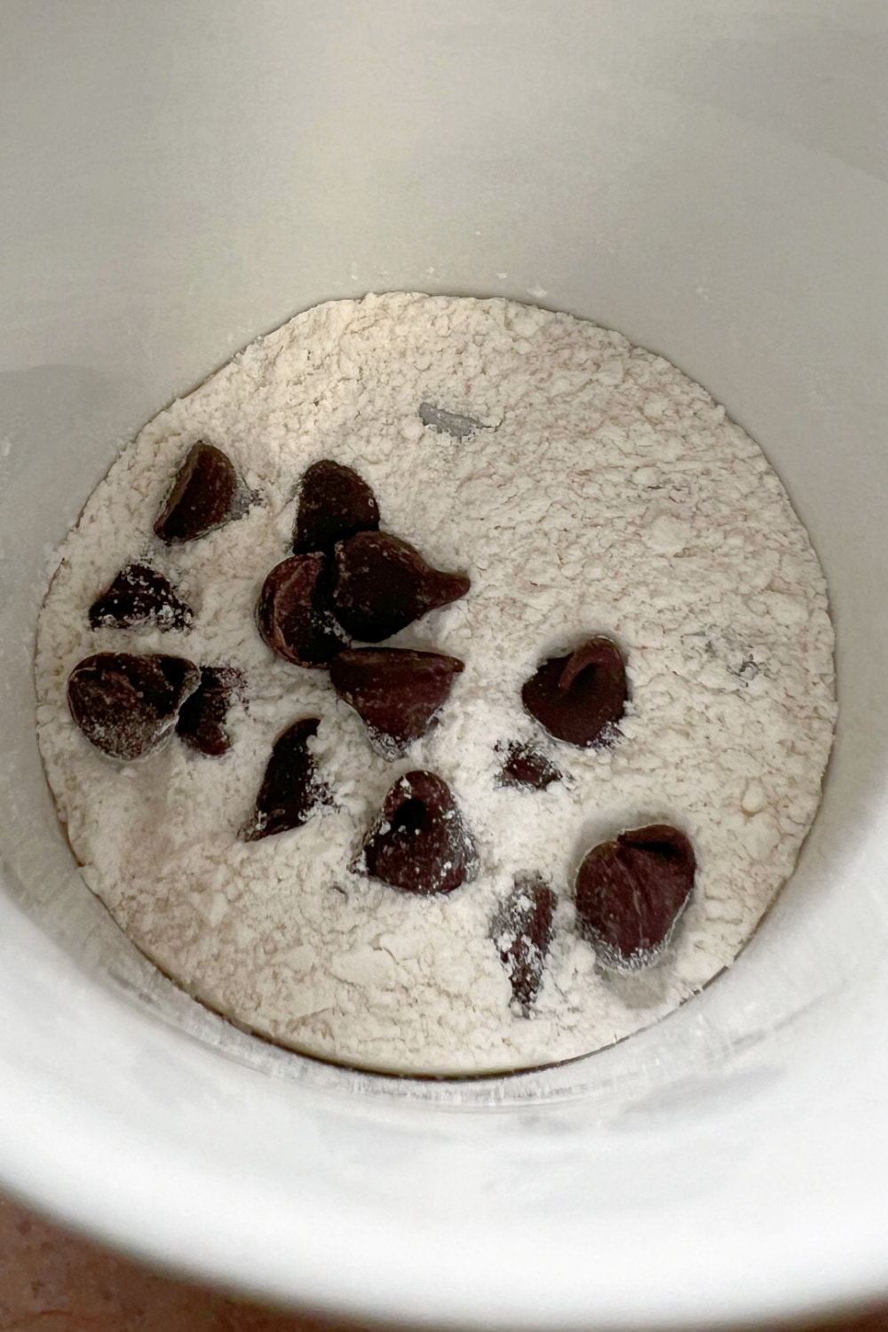 Dry ingredients with chocolate chips in a white cup. 