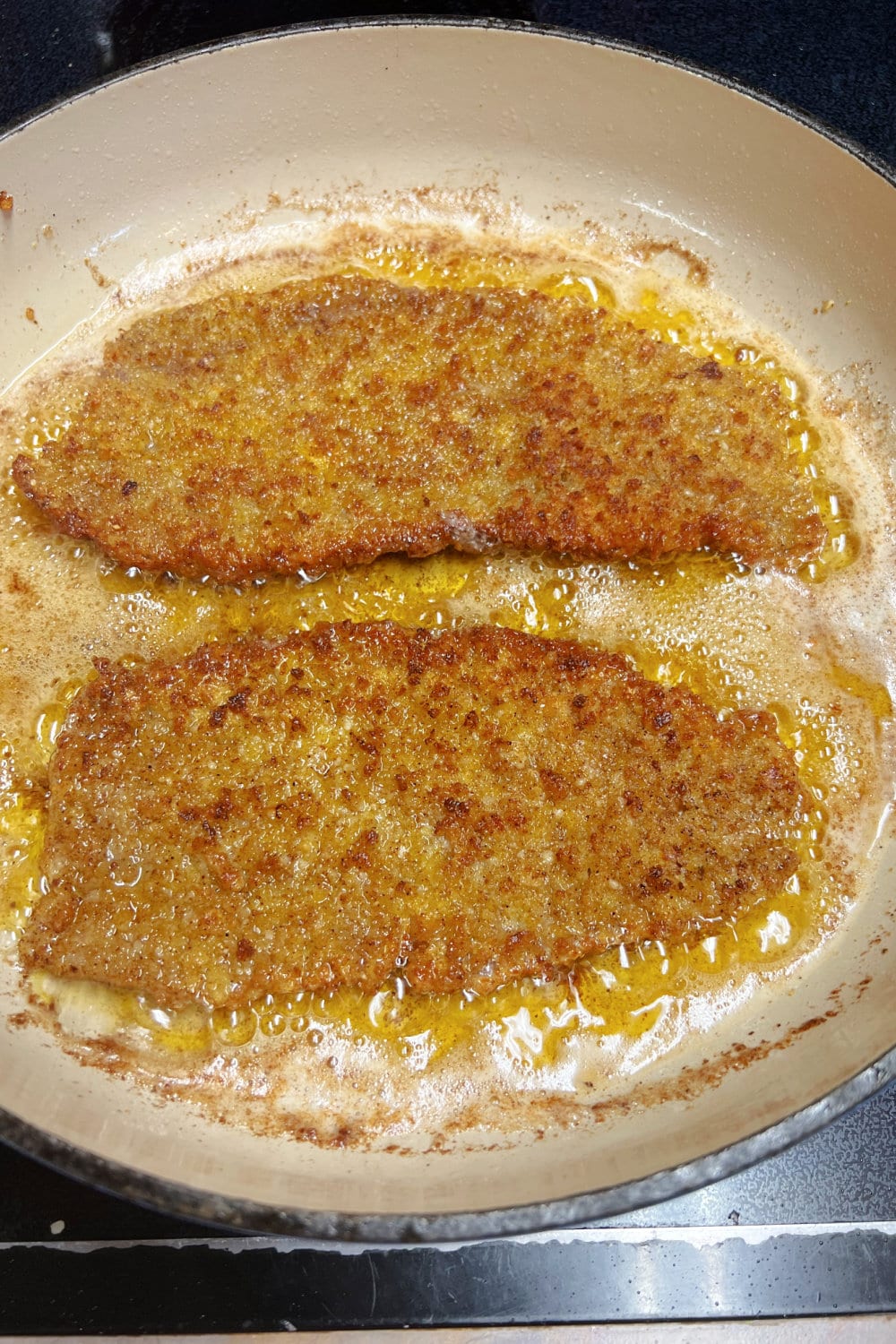 Golden brown Milanesa Steaks in a skillet. 