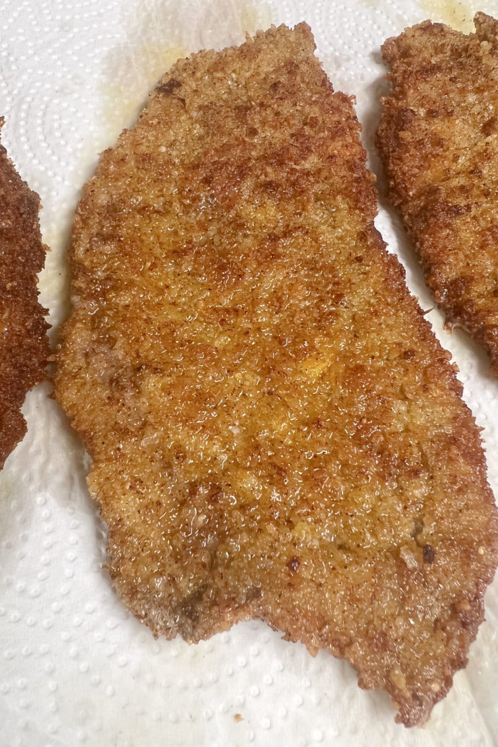 Freshly fried Milanesa Steak draining on paper towels. 