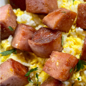 Cubes of fried Spam on top of scrambled eggs and rice.