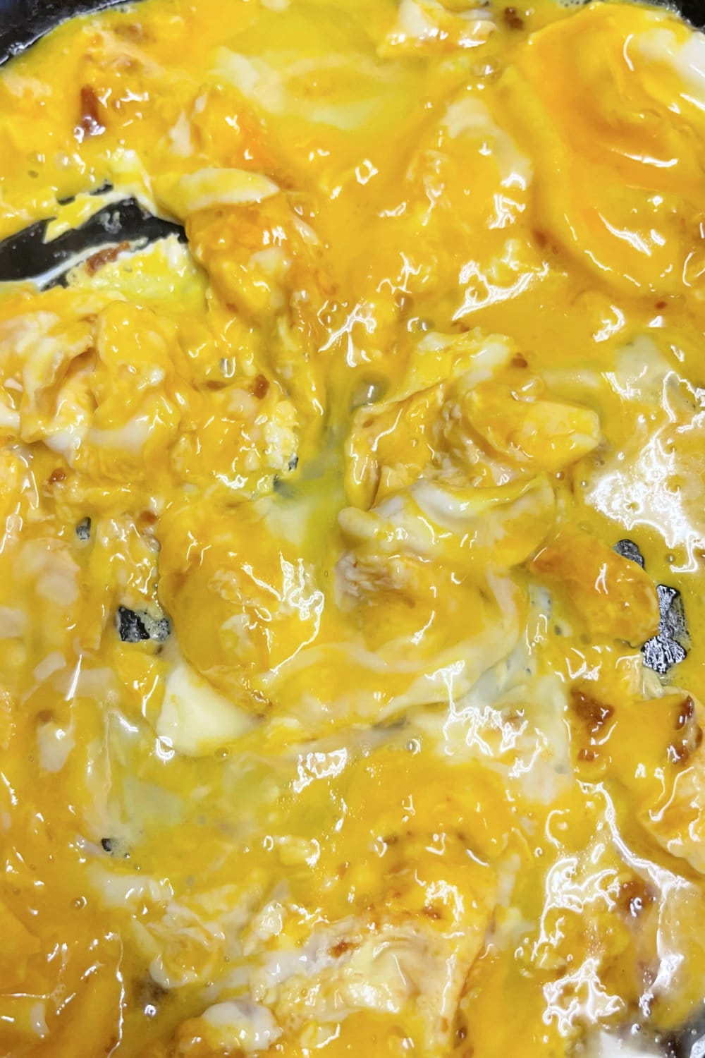 Scrambled eggs in a skillet beginning to cook.