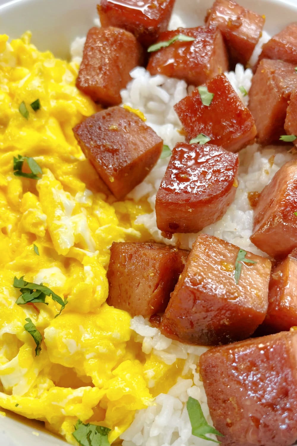 Browned cube of Spam with Scrambled Eggs and White Rice. 