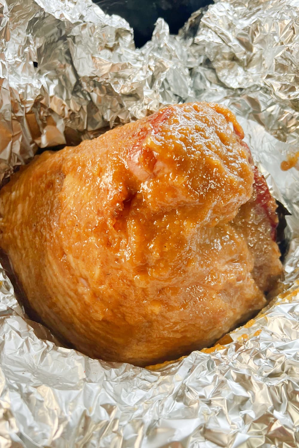 A partially cooked spiral ham that has just had glaze added to the foil packet. 