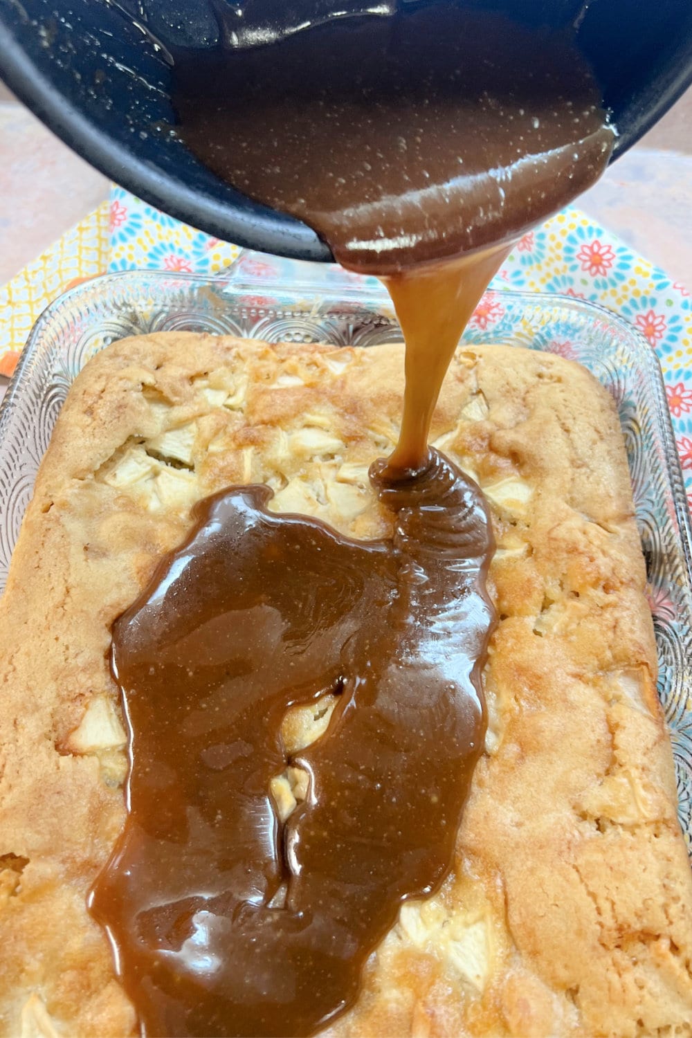 Pouring caramel sauce over the apple cake. 
