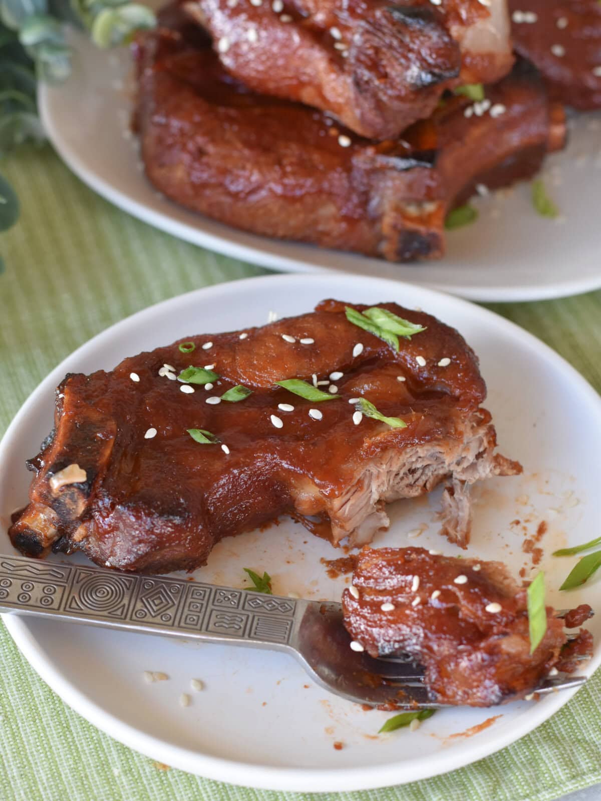 country-style-ribs-asian-bbq-plate Country Style Ribs with Asian BBQ Sauce on a white plate with more ribs on a plate stacked behind them.