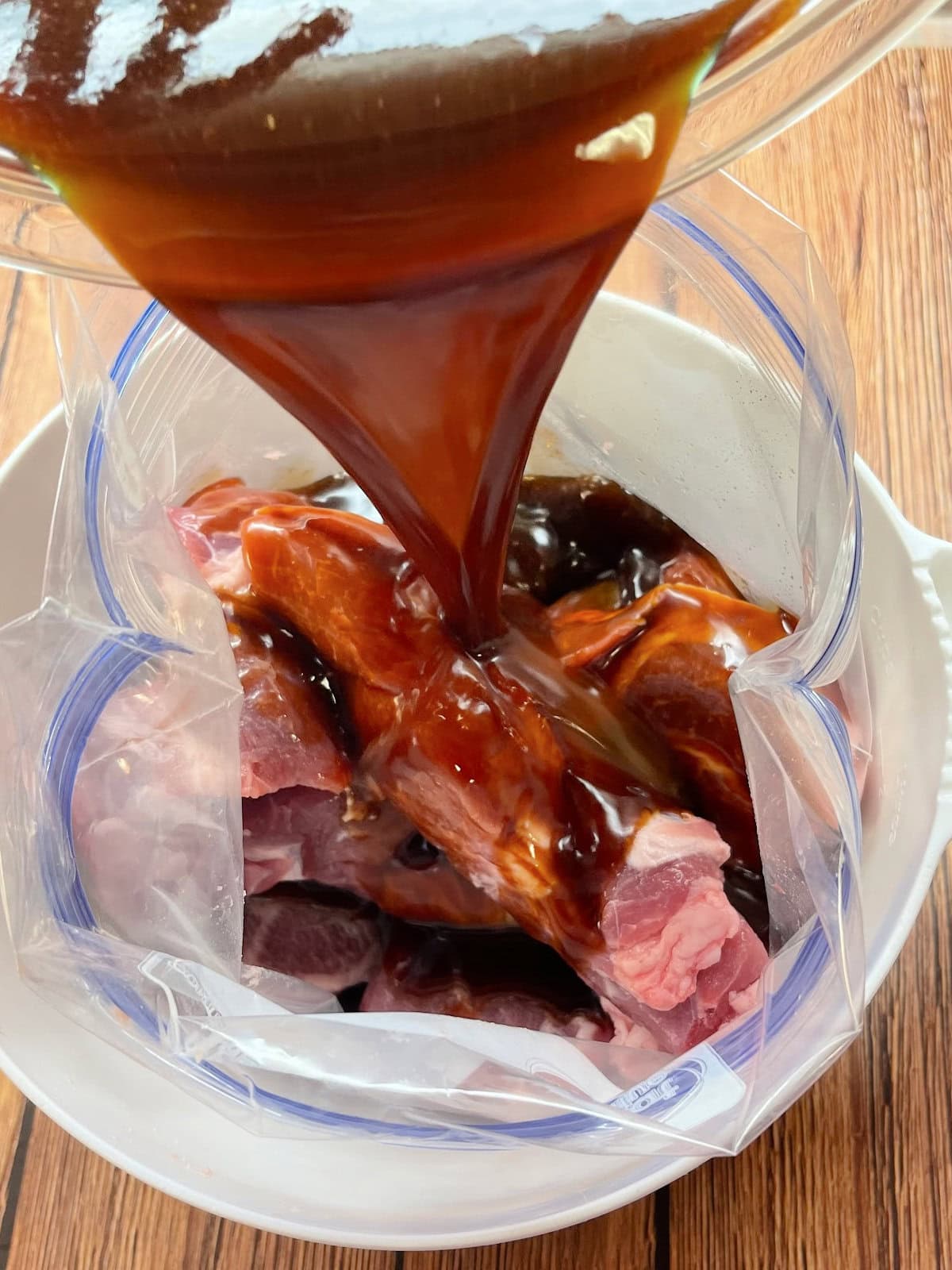 country-style-ribs-marinade-bag Ribs in a plastic bag with marinade being poured inside the bag.