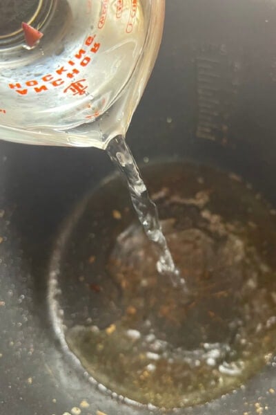 Water pouring into the Instant Pot from a measuring cup. 