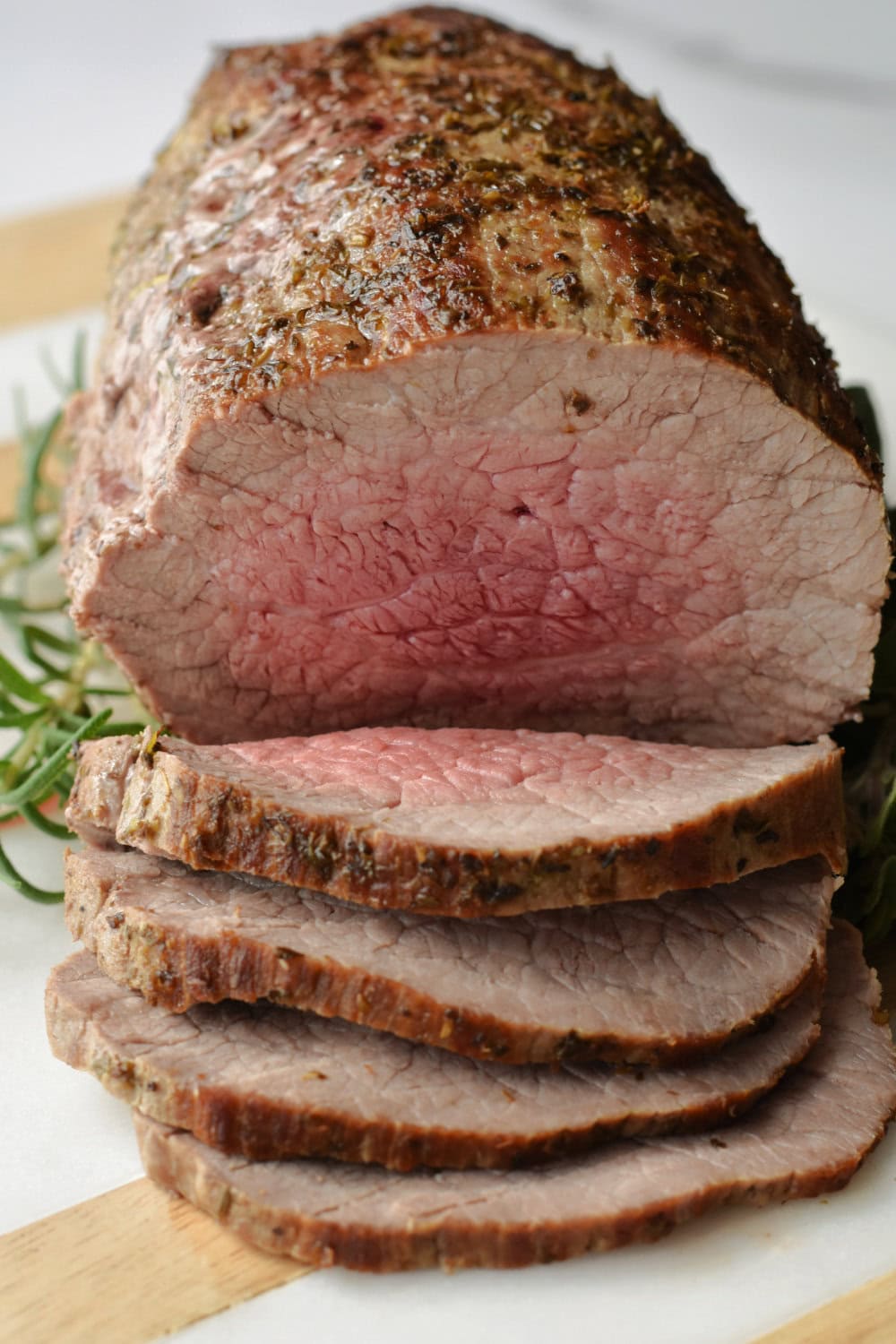 Medium-rare eye of round roast with one end carved into slices. 