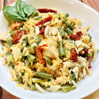 A bowl of Pesto Orzo garnished with almonds and Parmesan.