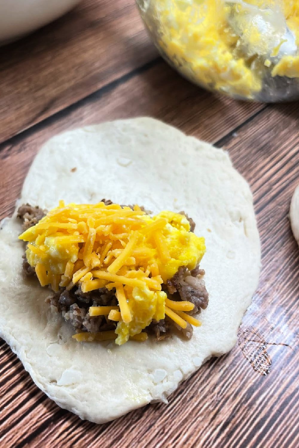 Adding the filling for a stuffed breakfast biscuit. 