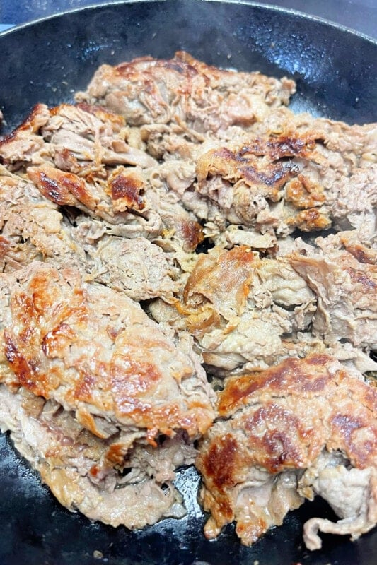 Fully cooked shaved steak in a skillet. 