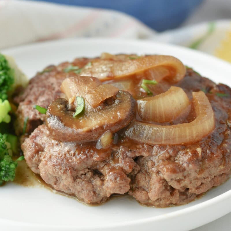 Hamburger Steak topped with sauteed onions on a white plate.