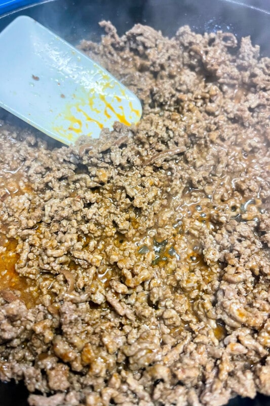 Seasoned ground beef simmering in a skillet. 