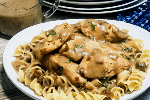 Instant Pot Chicken Tenders with gravy served on a plate with gravy behind in a serving dish. 