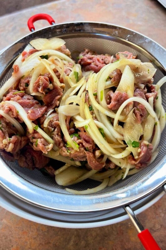 Straining the steak and onions from the marinade. 