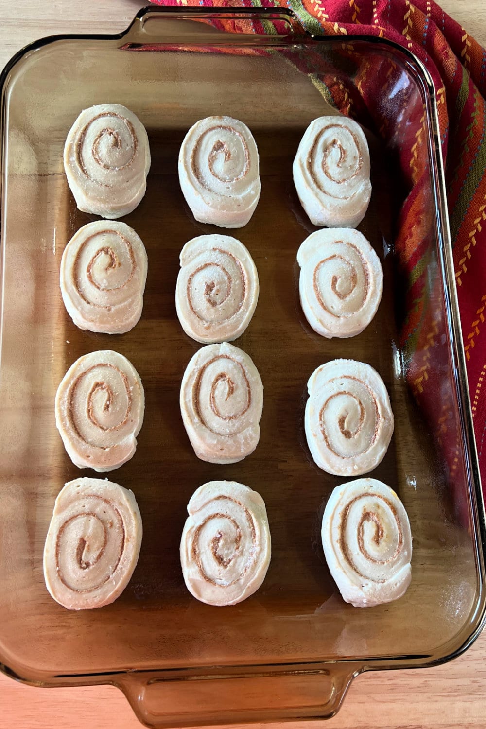 Frozen cinnamon rolls placed into a greased baking dish. 