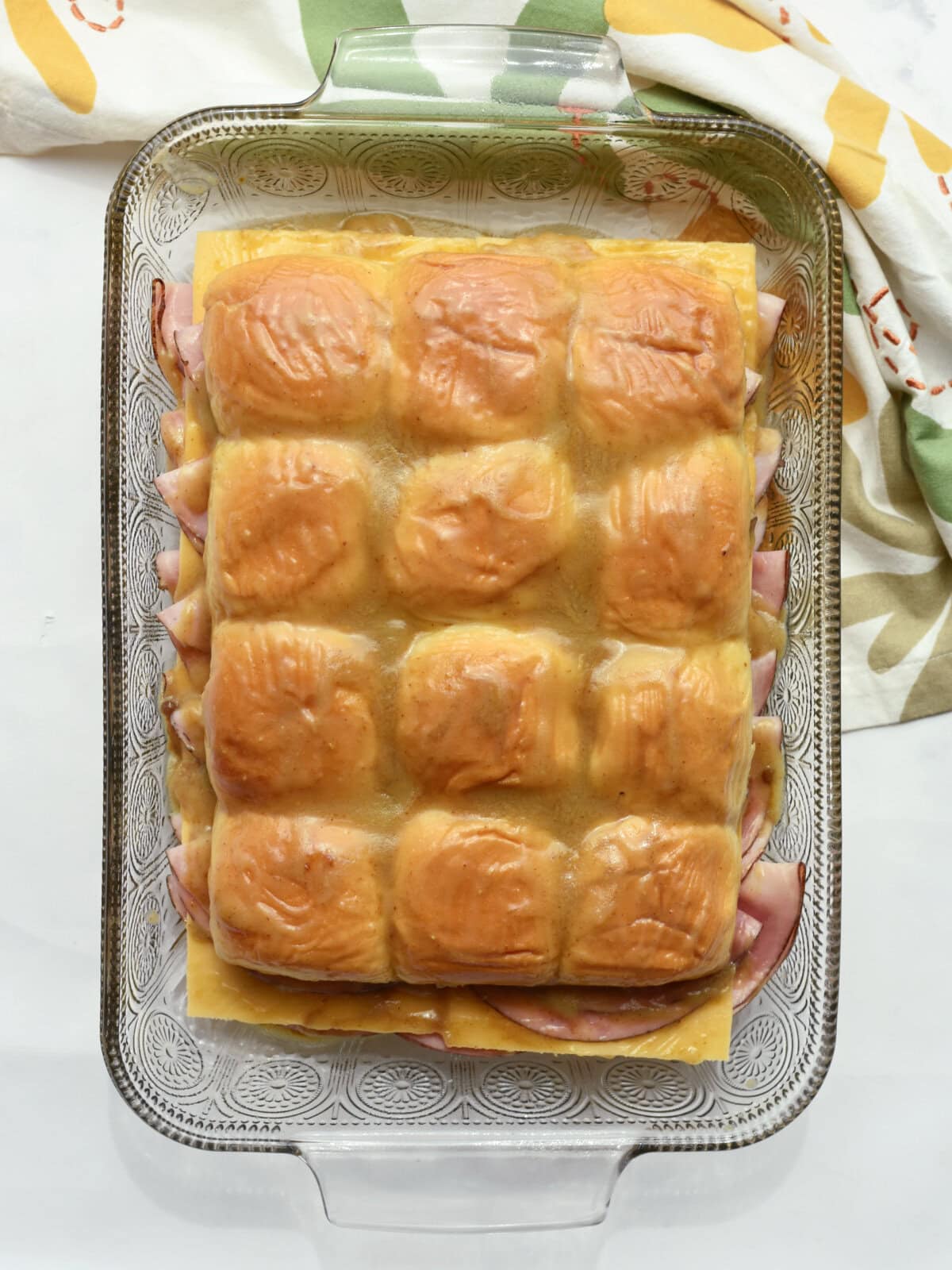 Buttered pan of party sandwiches ready to cook in the oven. 