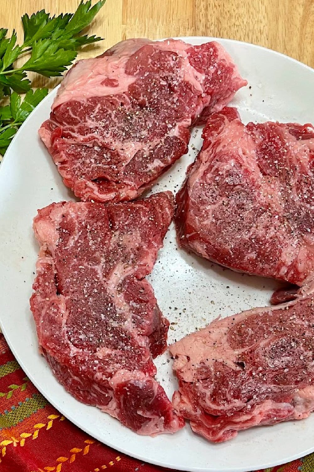 Seasoned chuck eye steaks resting at room temperature.