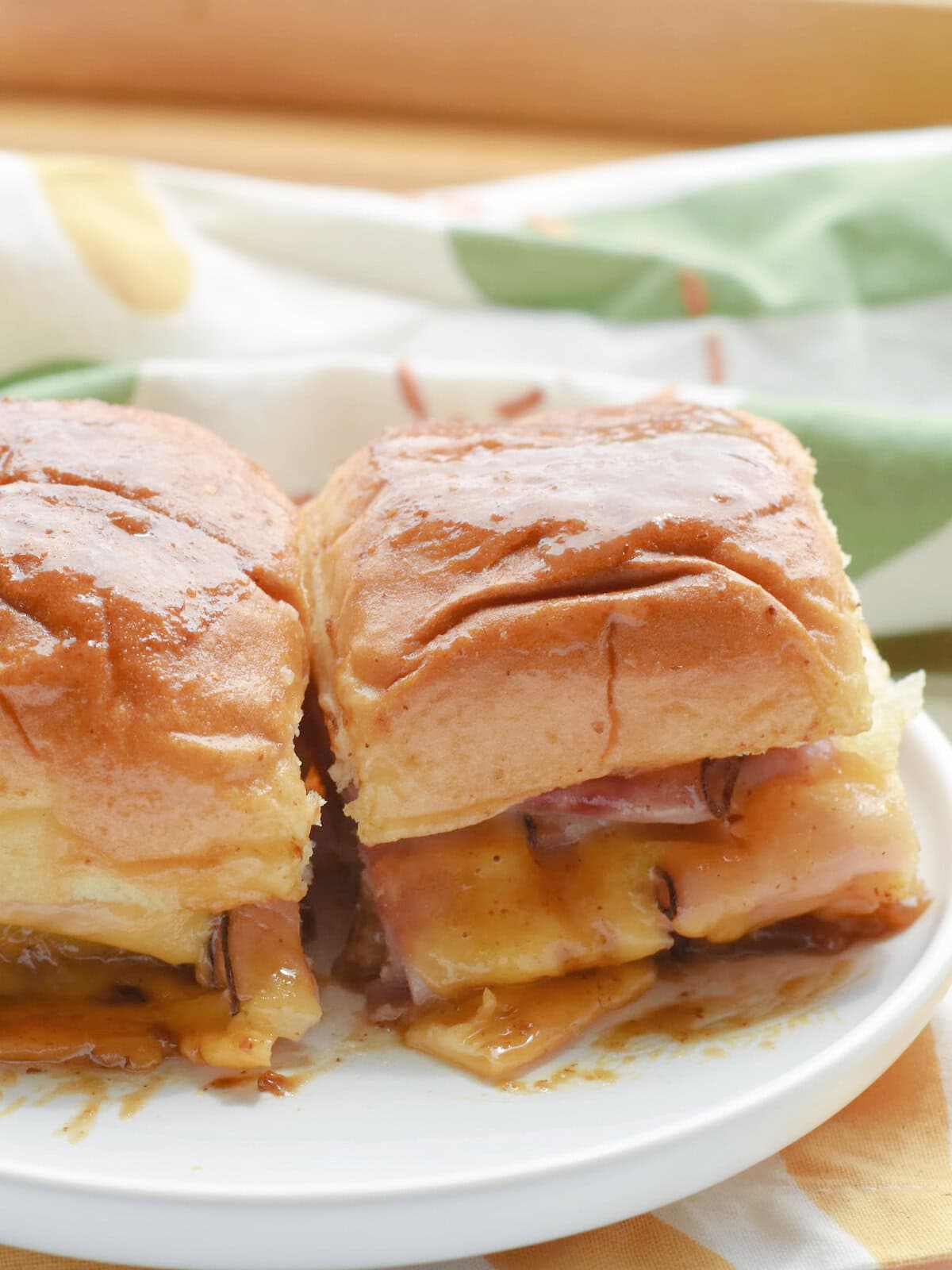 Kings Hawaiian Ham and Cheese Sliders on a white platter with buttery sauce. 