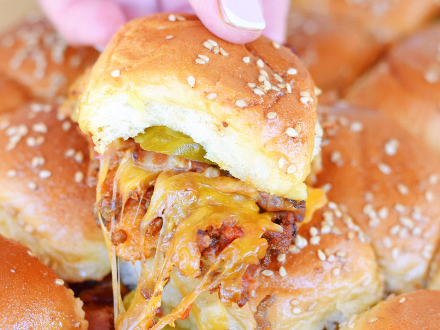 A hot and fresh Bacon Cheeseburger Slider being pulled from the pan.