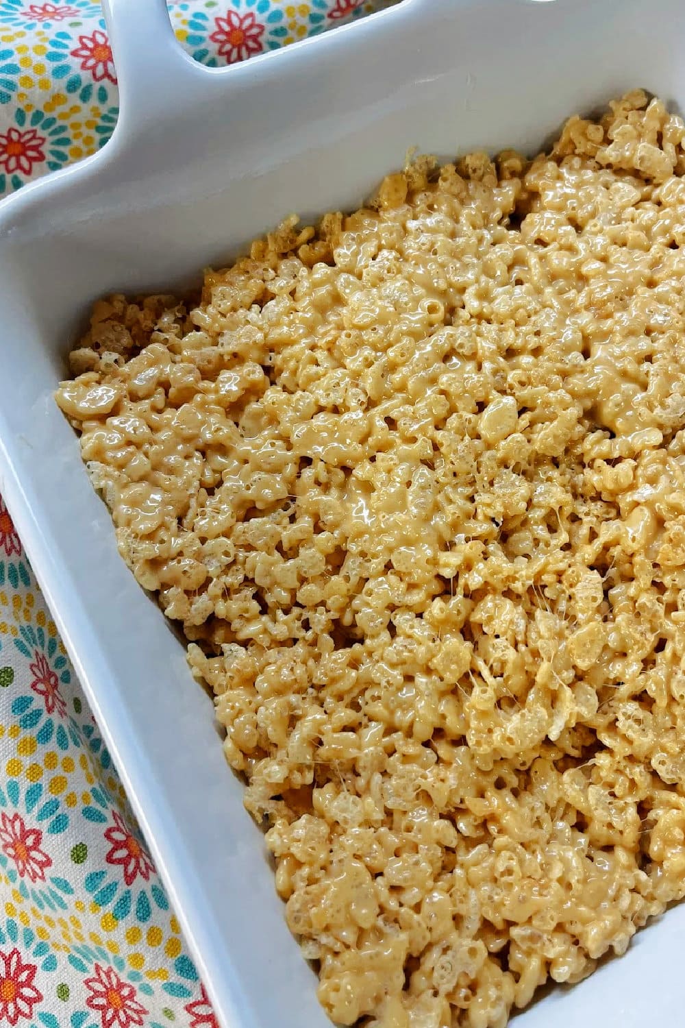 Peanut butter rice krispie treats mixture pressed into a white baking dish. 