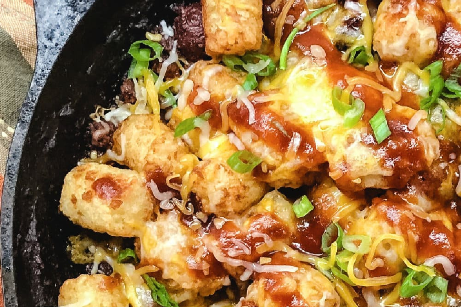 BBQ beef casserole with tater tots in a cast iron skillet. 