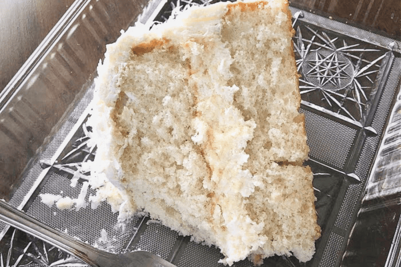 White cake from a box mix that is extra moist on a clear plate. 