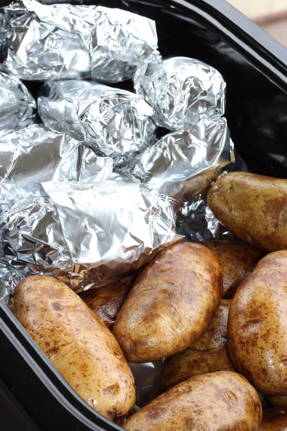 Baked potatoes in a roaster, half of them wrapped in foil. 