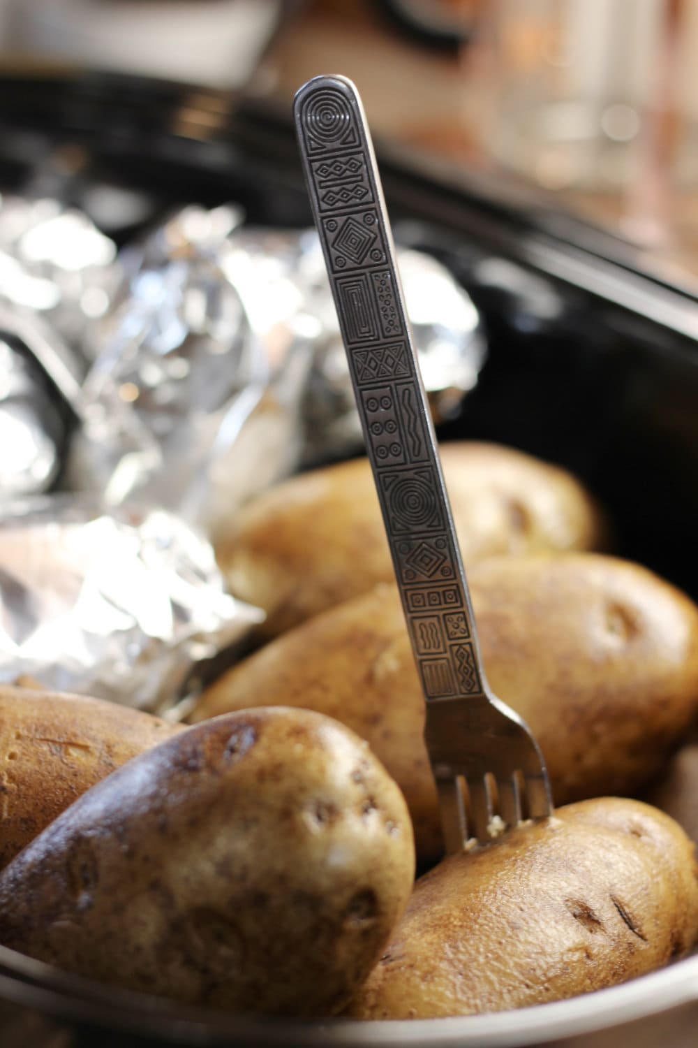 Piercing a baked potato with a fork to be sure it's fully cooked and tender inside. 