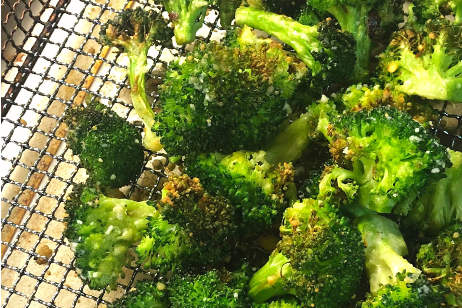 Air fryer broccoli with parmesan cheese in a air fryer basket. 