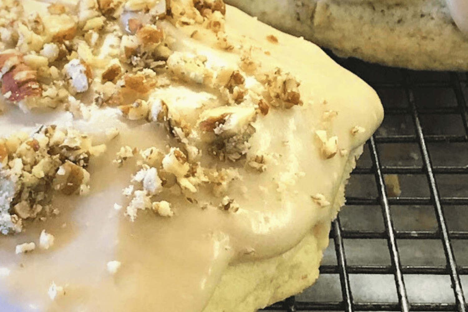 Maple pecan scones on a cooling rack with pecans over top. 