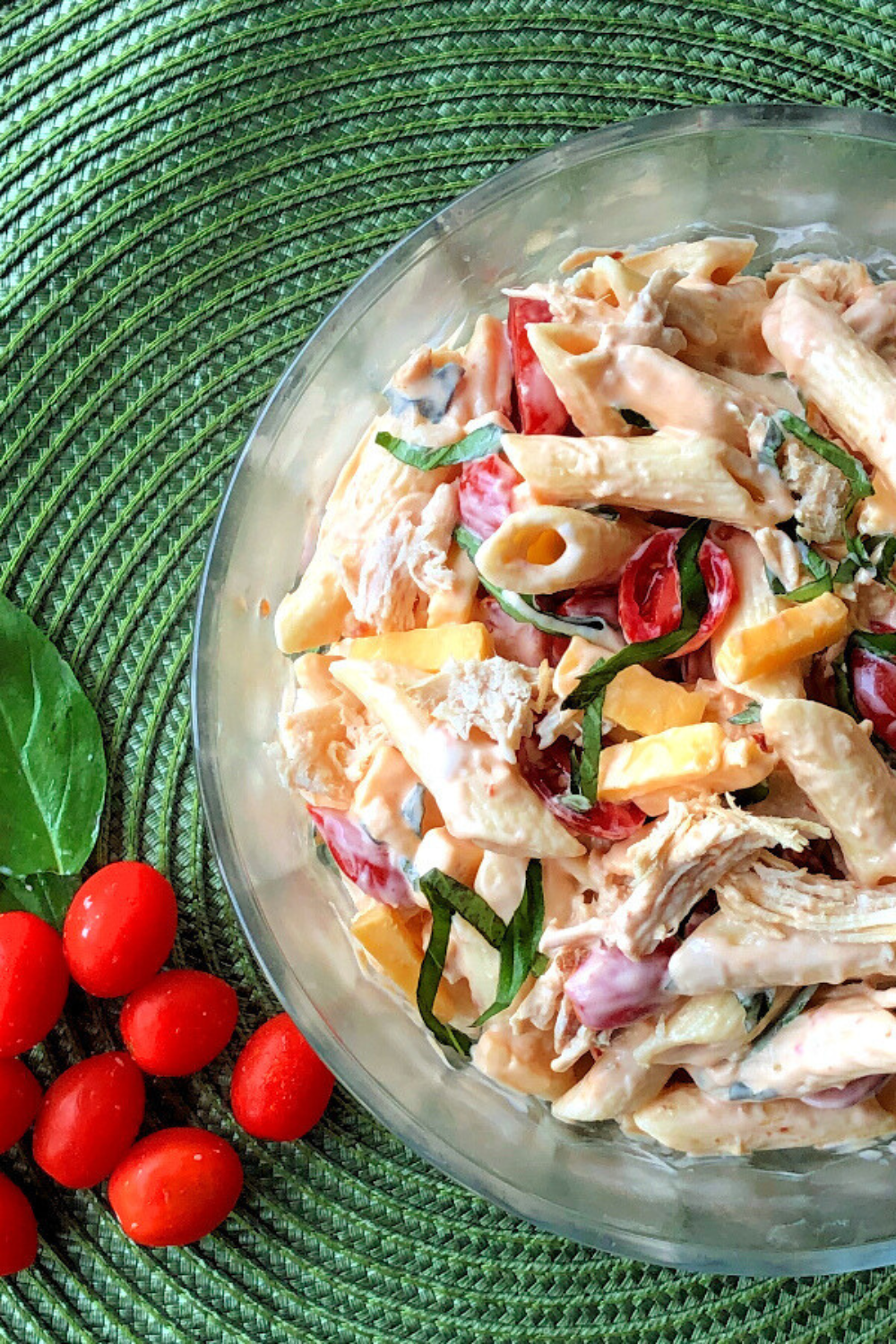 Chipotle pasta salad with chicken in a clear bowl with cherry tomatoes. 