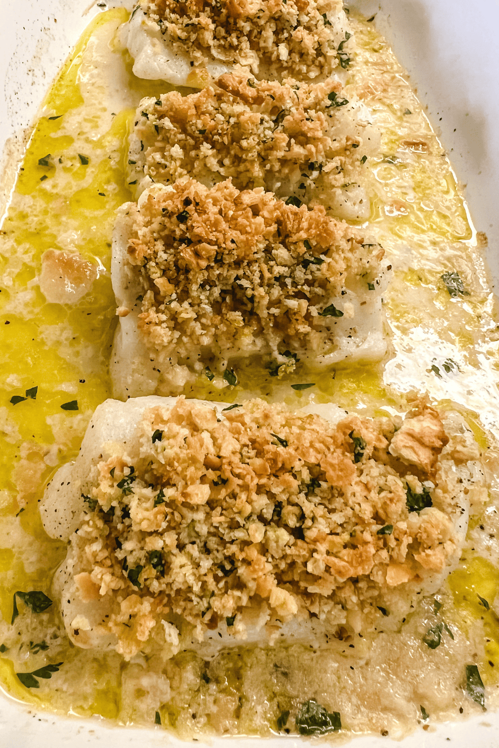 Baked cod filets with a buttery cracker topping in a cooking dish. 