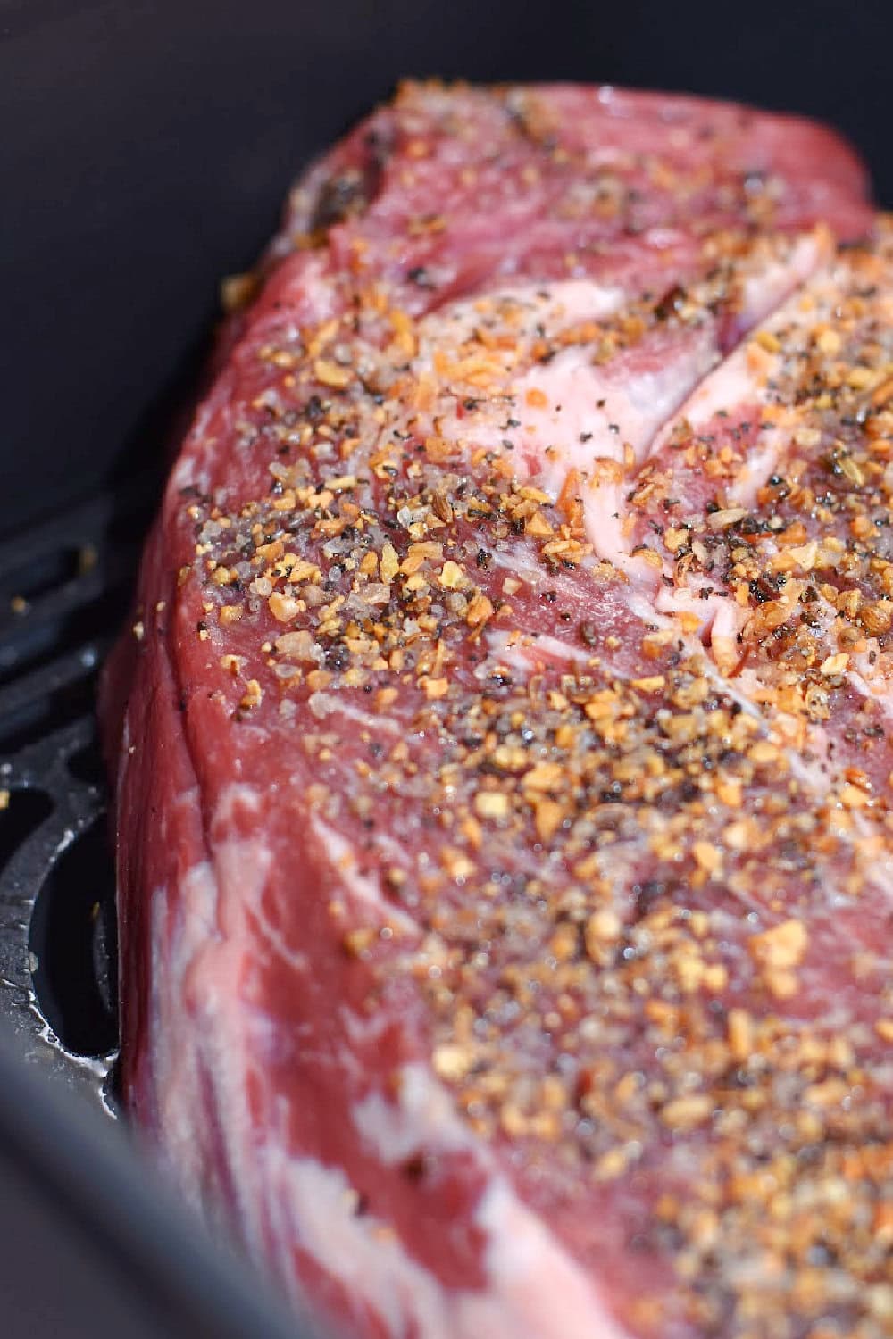 The seasoned chuck roast, placed into the air fryer to sear. 