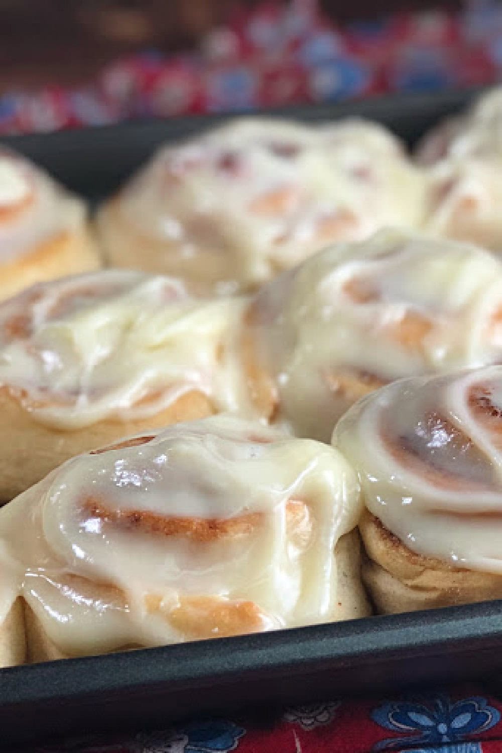 Frosted homemade cinnamon rolls in a pan. 