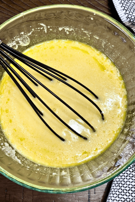 Vanilla, egg, applesauce, milk and vegetable oil for moist chocolate muffins mixed in a bowl. 