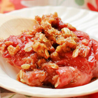 A wooden spoon with strawberry crumble on it.