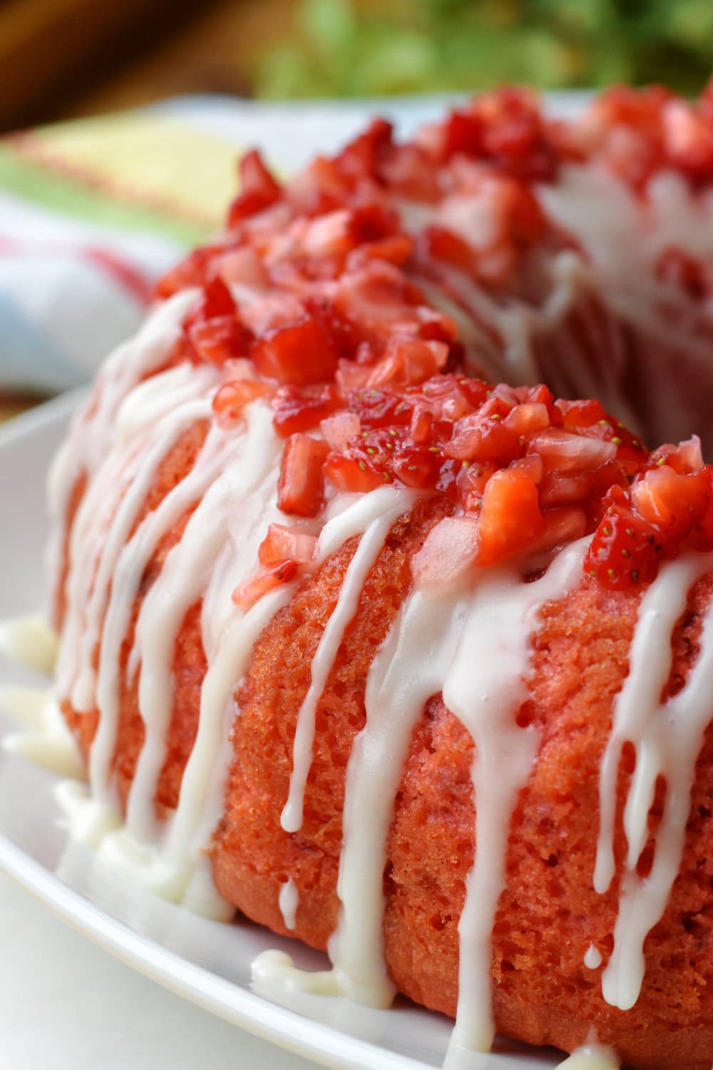 A pound cake that is glazed and topped with chopped strawberries. 