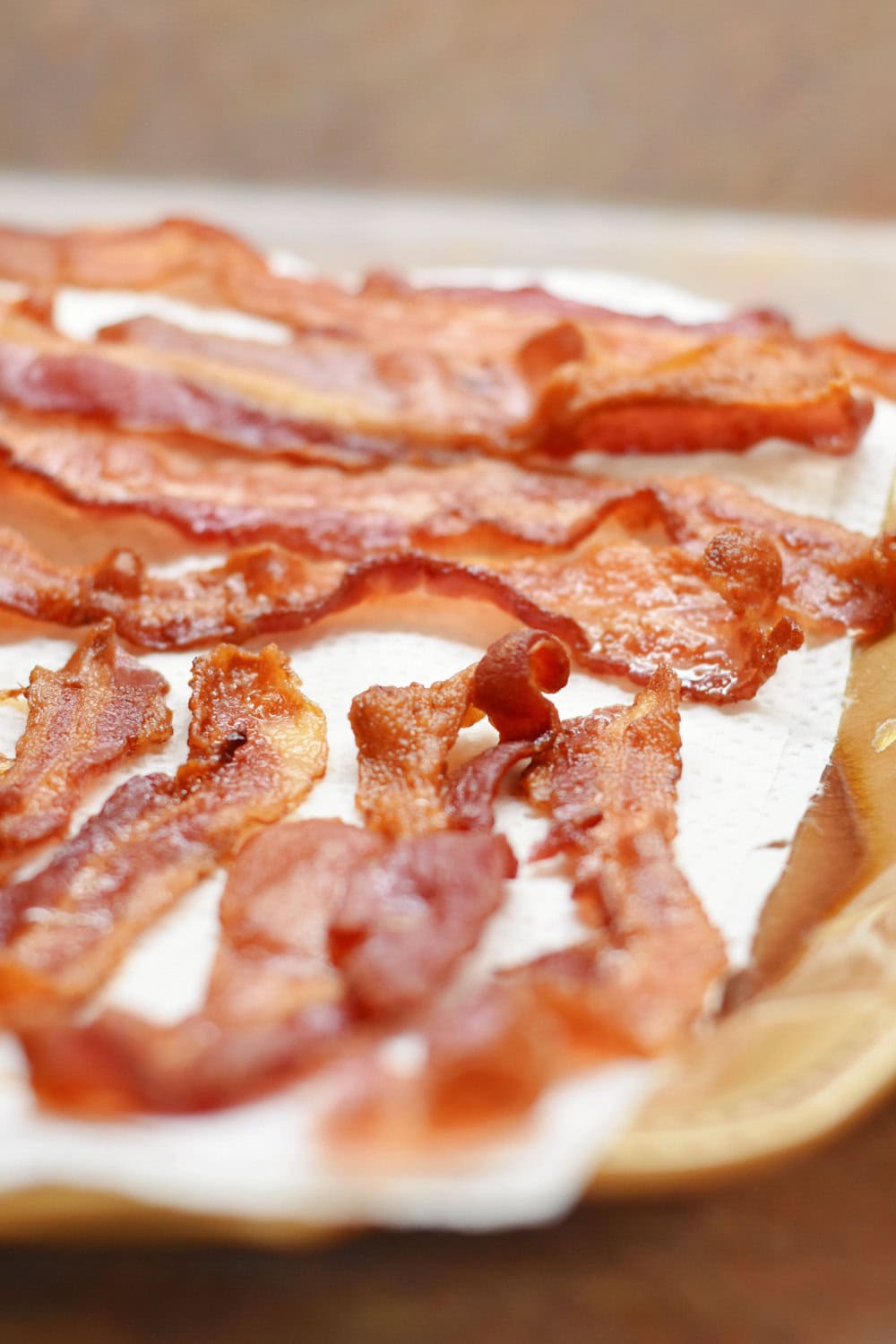 Slices of cooked bacon on a paper towel-lined plate. 