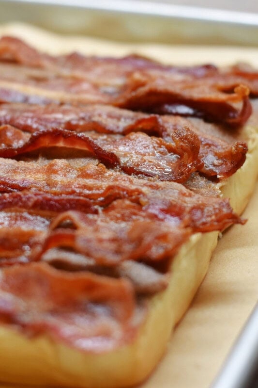 Slices of crispy bacon on top of the buttered cinnamon rolls. 