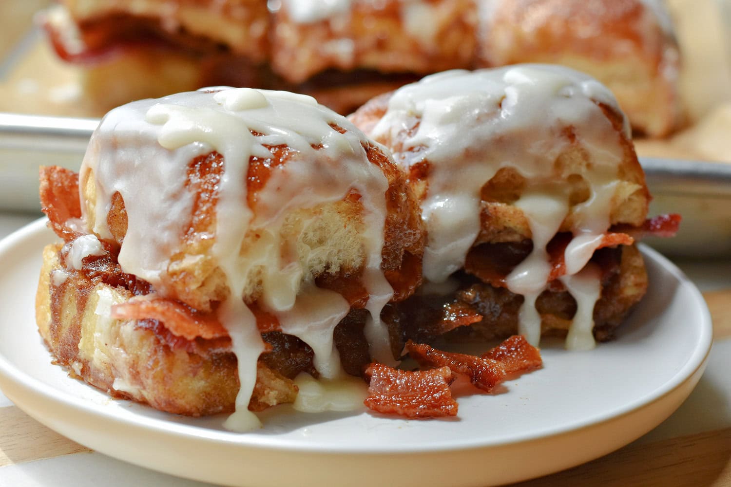 Two Bacon-Stuffed Cinnamon Rolls on a white plate. 