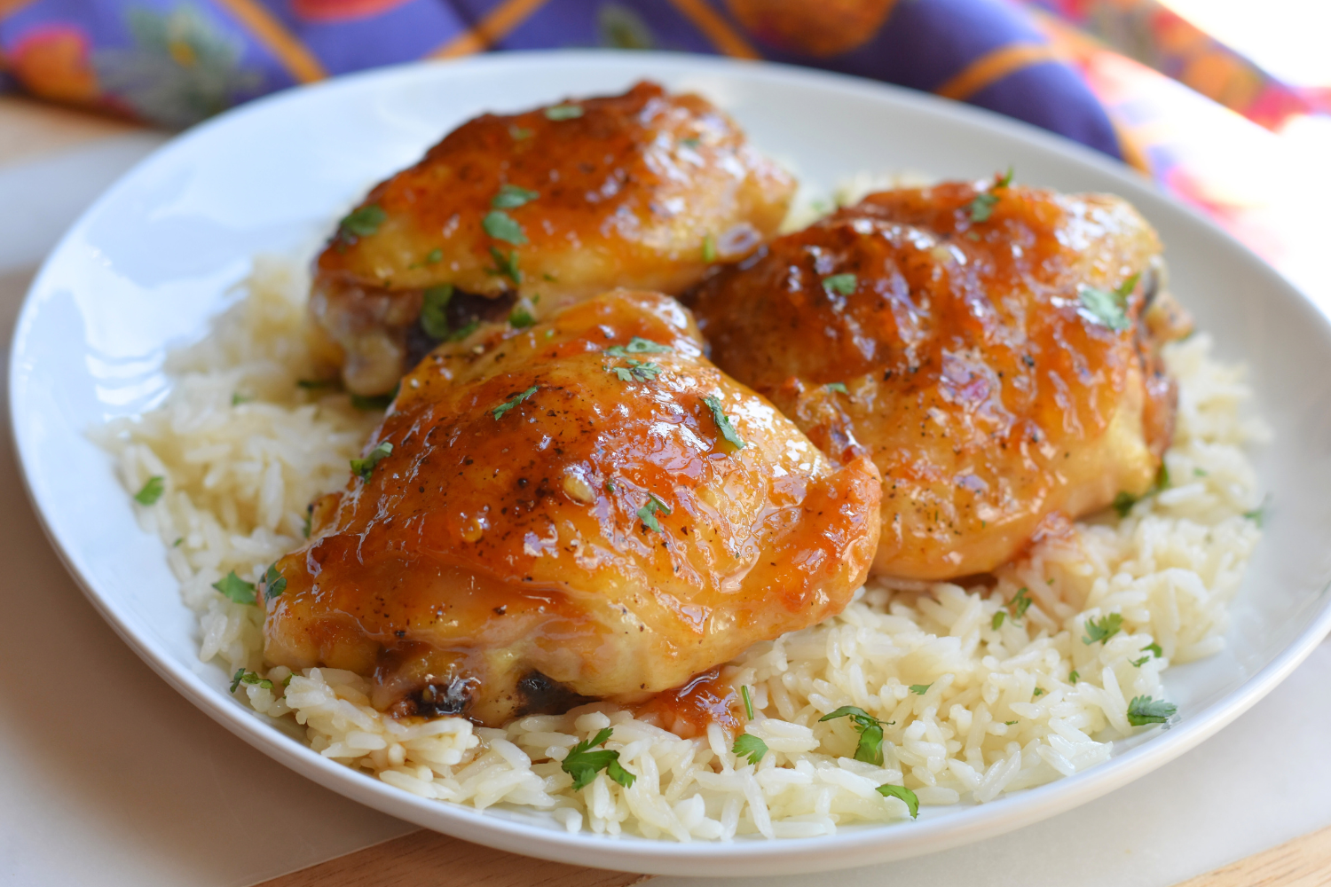 Sticky Asian Chicken Thighs over warm Jasmin rice in a white bowl. 