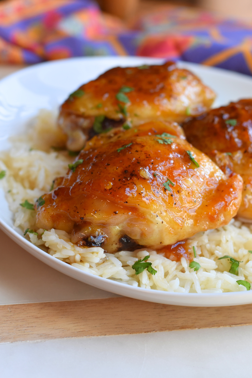 A sticky chicken thigh covered with asian sauce over a bed of rice. 