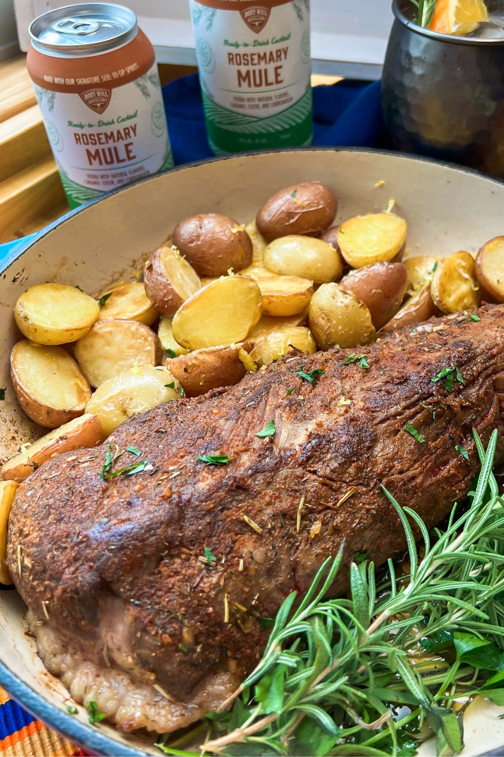 Roasted beef tri tip in a cast iron skillet with potatoes and garnish. 