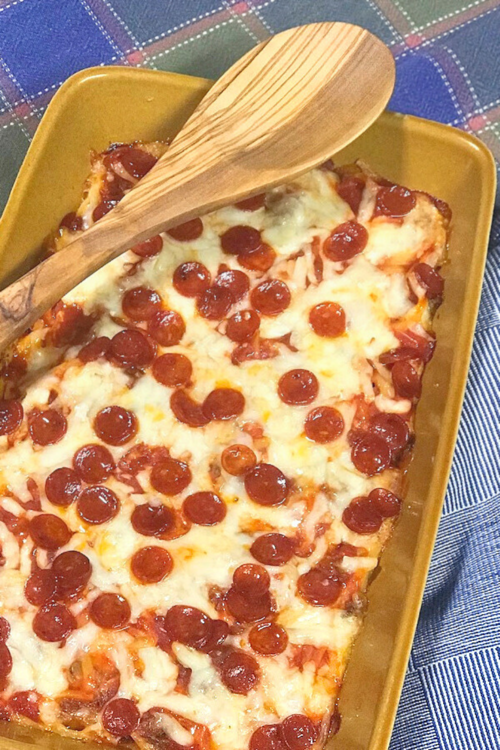 A pan of fresh zucchini pizza casserole on a blue tablecloth. 