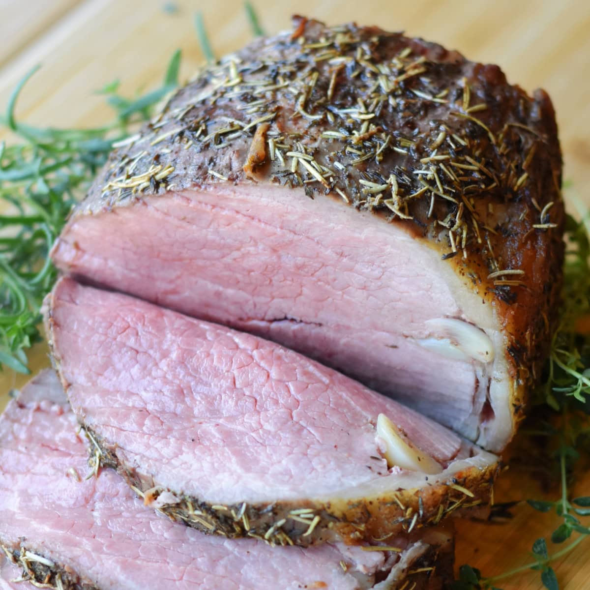 Slices of Garlic Butter Eye of Round next to the whole roast.