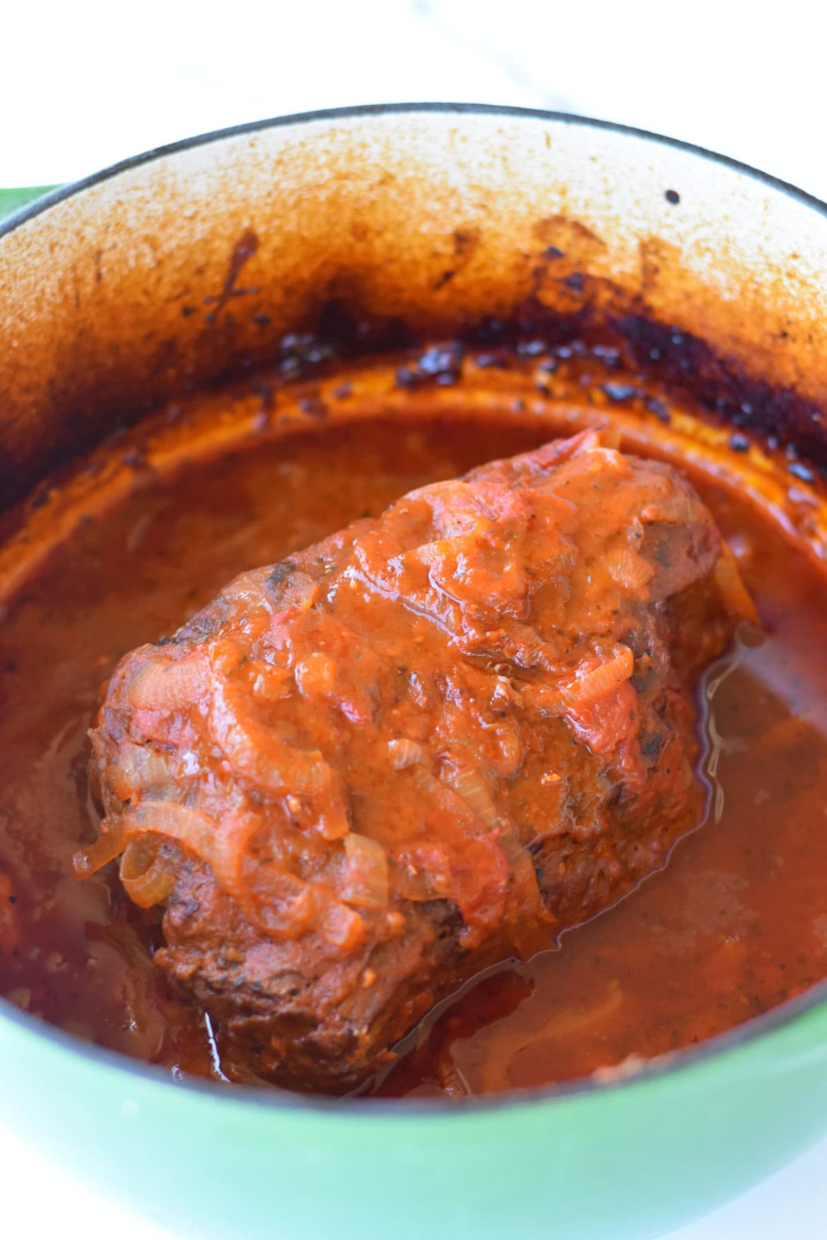 Beef bottom round roast recipe in a pot braising in Italian tomatoes and flavors. 