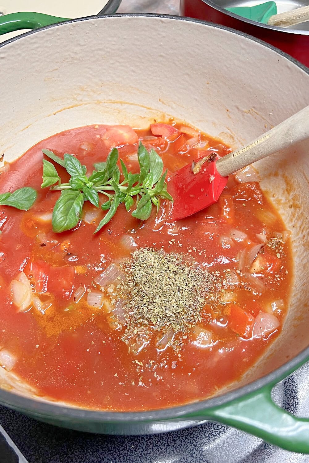 Tomato sauce in a Dutch oven with fresh basil added. 