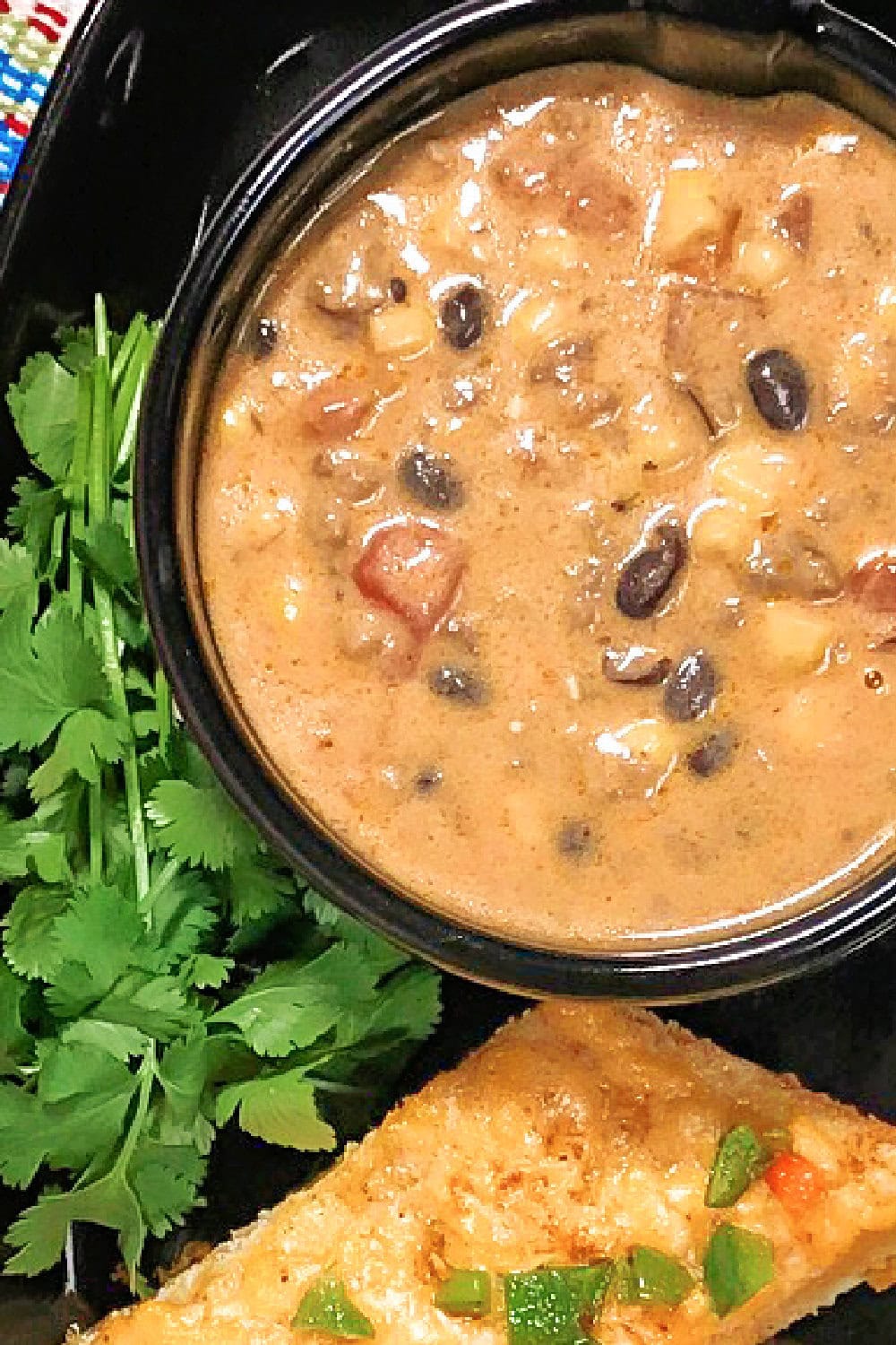 Taco soup with ground beef and black beans in a bowl with mexican bread. 