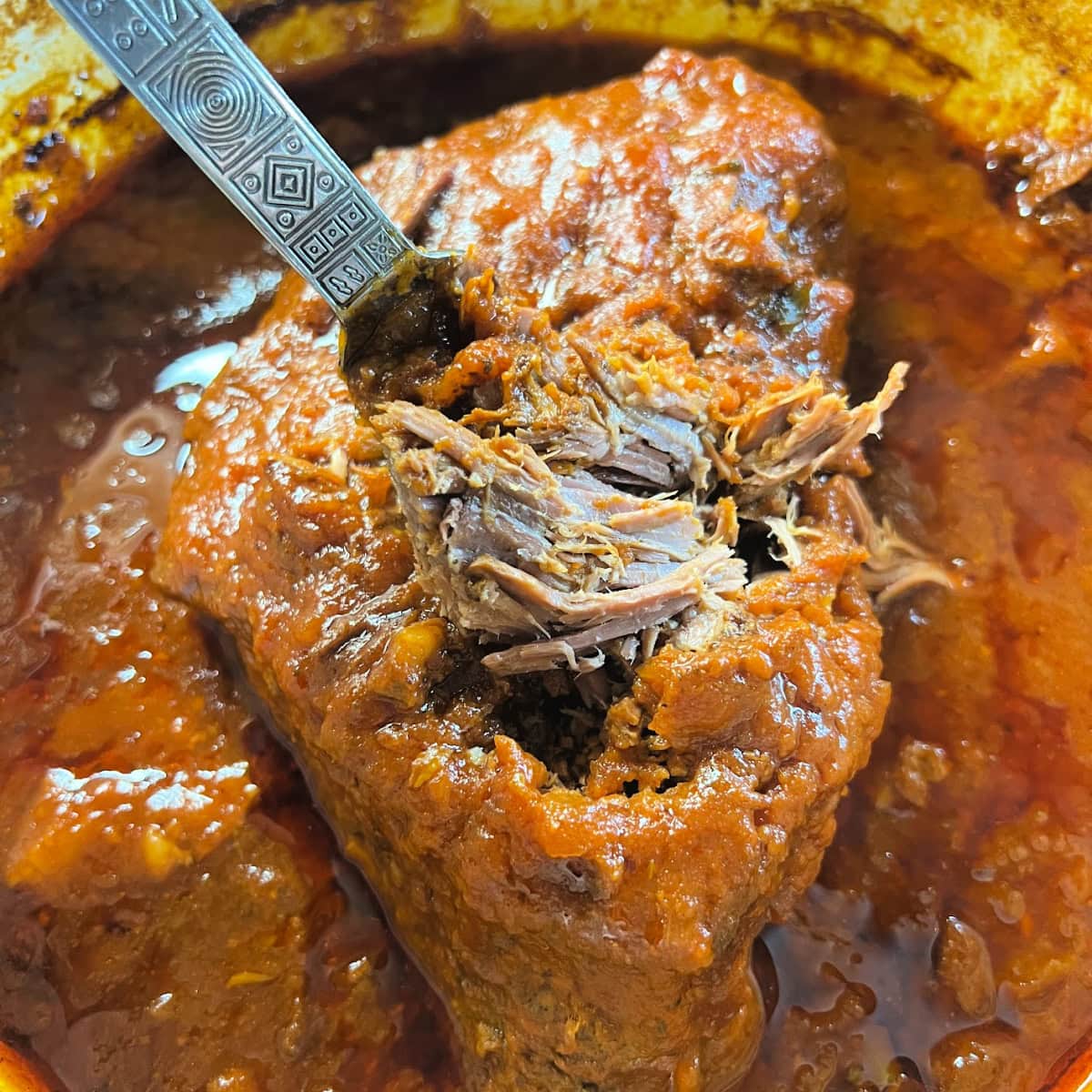 Fork tender beef bottom roast simmering in Italian seasonings.
